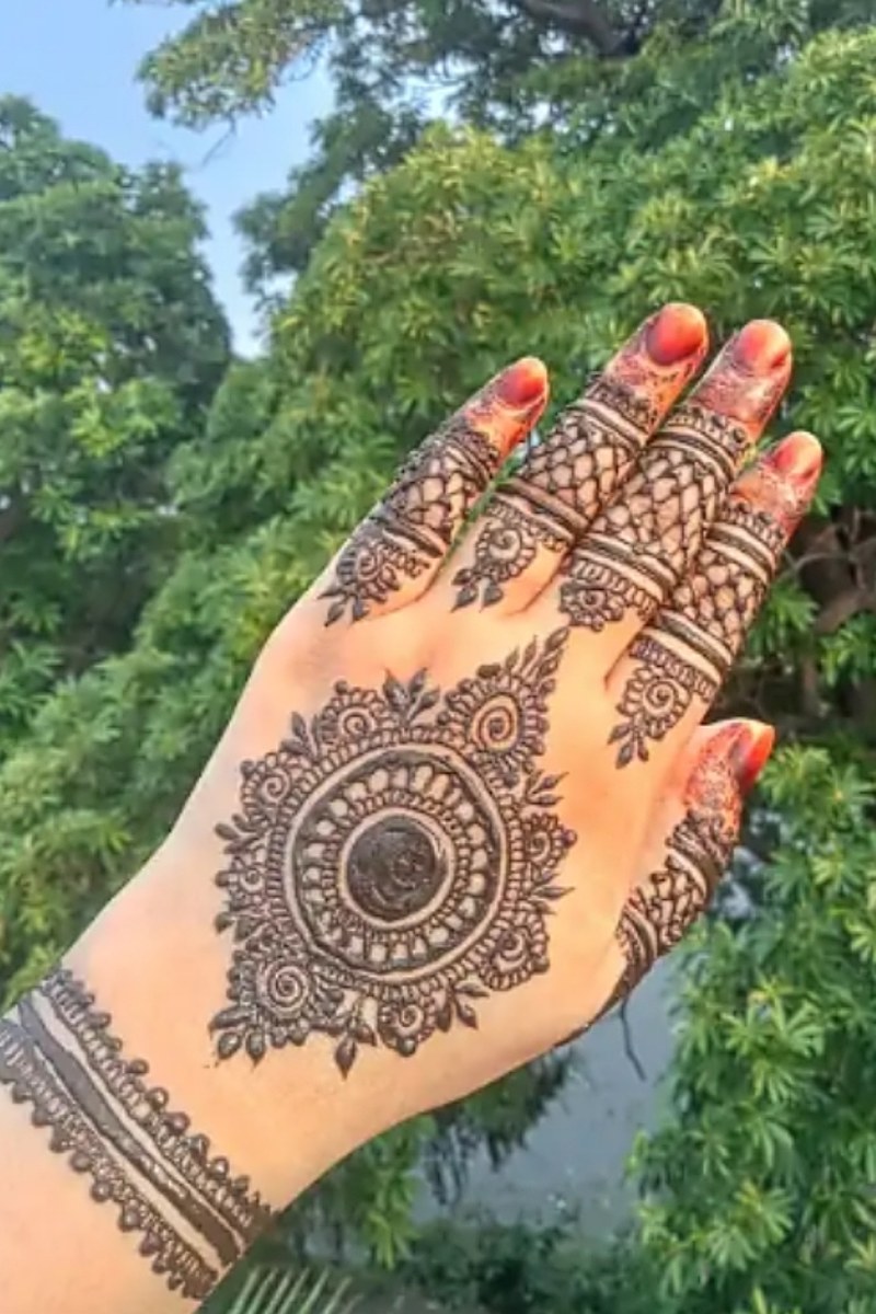 Mandala mehndi design on the back of the hand with finger bands